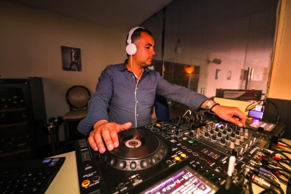 DJ concentré en train de mixer sur une table Pioneer dans un club, casque sur les oreilles